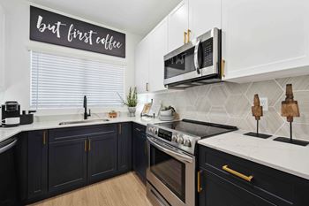 A kitchen with dark cabinets and a white countertop with a sign that says "but first coffee".